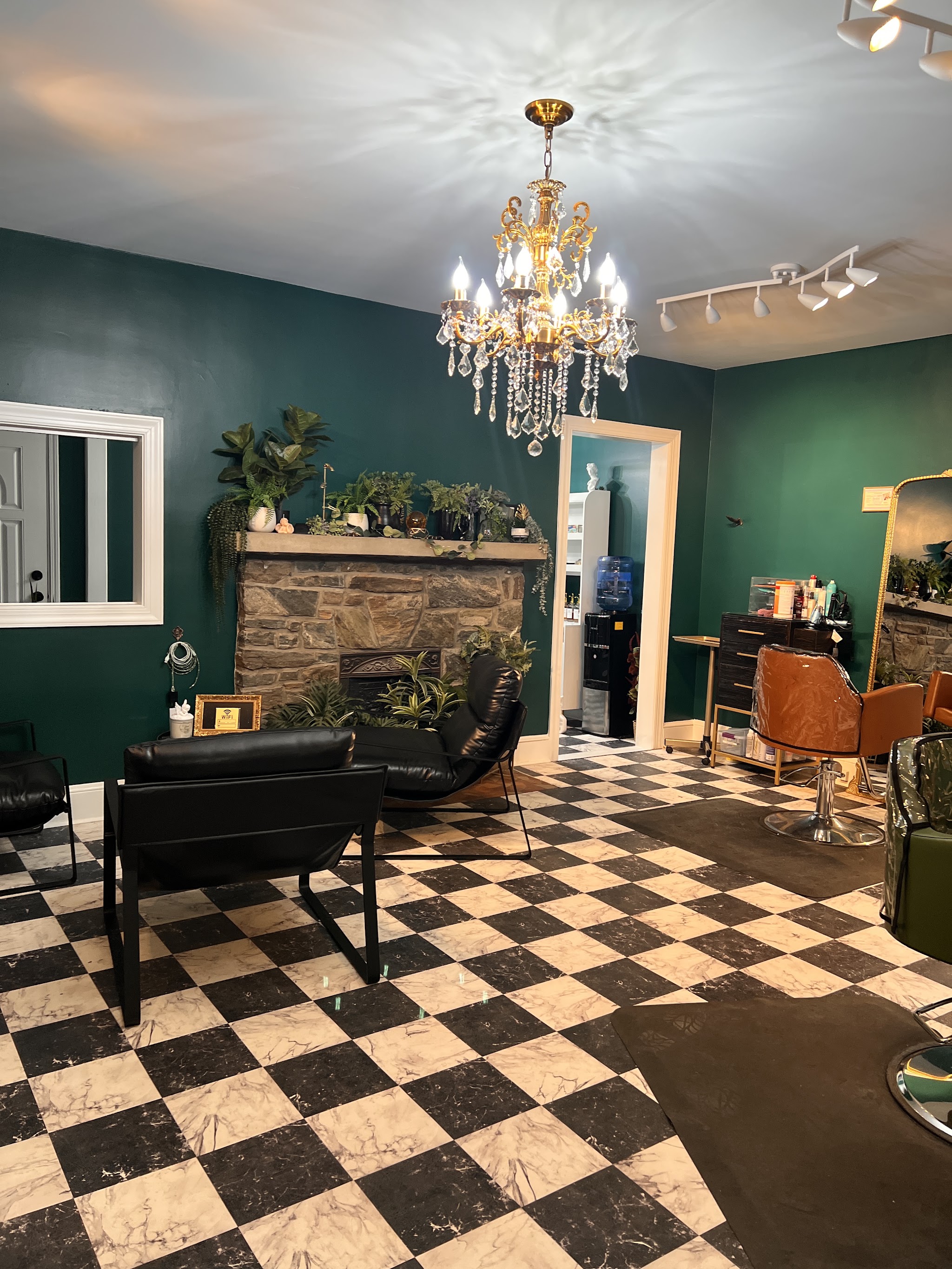 Inside the salon: emerald walls, a stone fireplace, a gold chandelier and a checkerboard floor